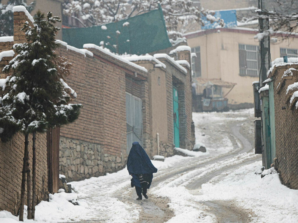 <p>A burqa-clad woman walks along a street during snow fall in Kabul on January. Photo: AFP</p>