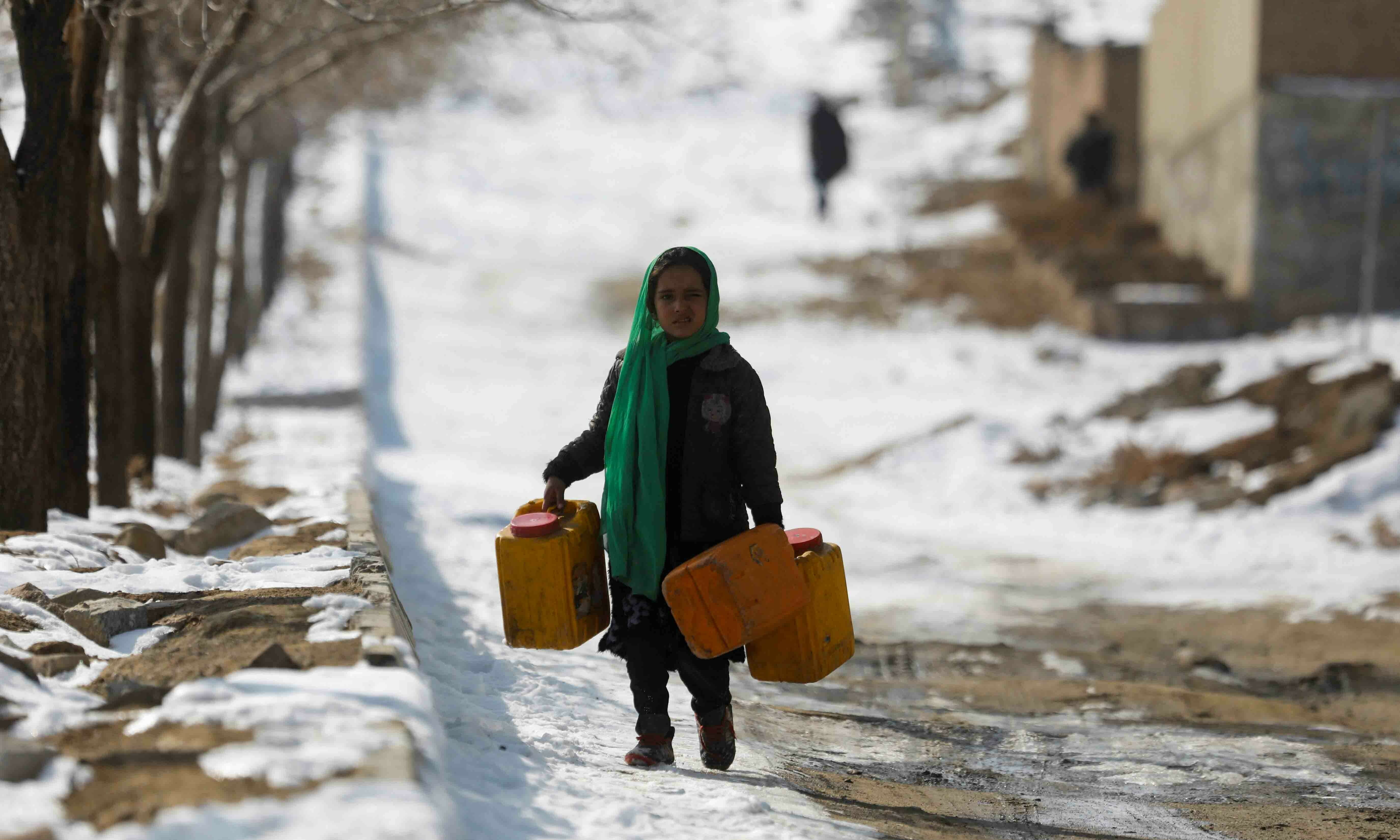 <p>An Afghan girl carries empty water containers on a snow-covered street in Kabul, Afghanistan, January 26. — Reuters</p>