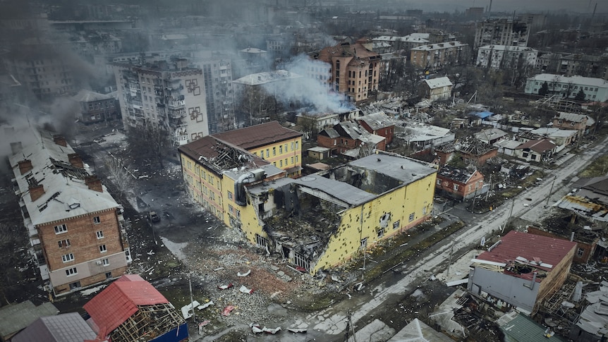 An aerial view of Bakhmut shows many damaged houses and smoke rises from some buildings.