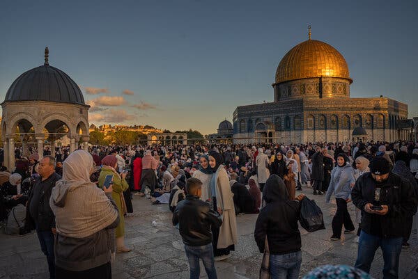 Crowds of people, including women wearing head scarves, are seen at the Al Aqsa mosque at sunset.