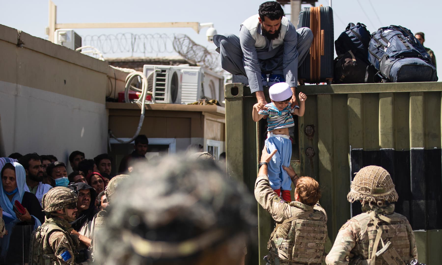 An Afghan man hands his child to a British Paratrooper assigned to 2nd Battalion, Parachute Regiment while a member of 1st Brigade Combat Team, 82nd Airborne Division conducts security at Hamid Karzai International Airport in Kabul, Afghanistan on August 26, 2021. — AP