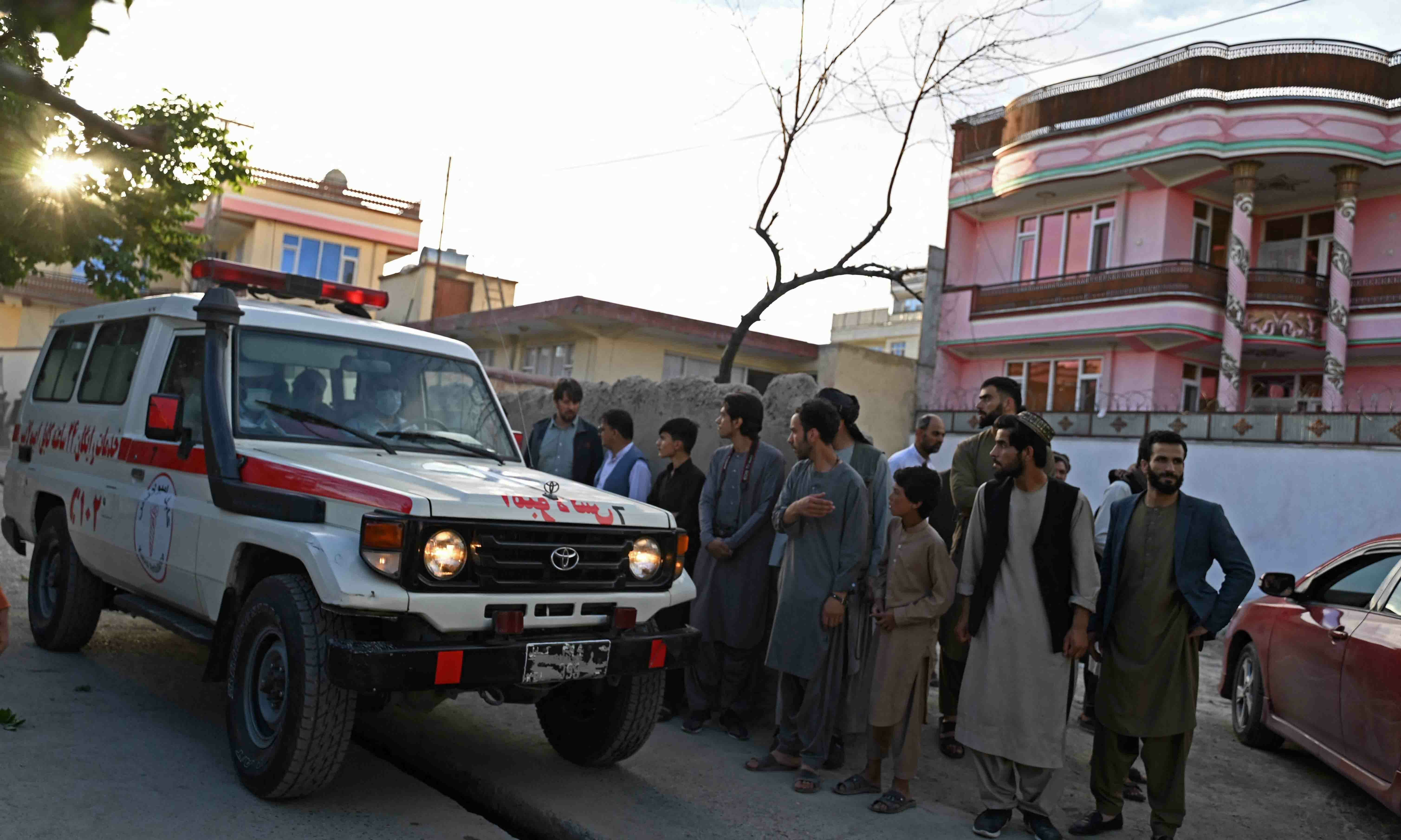 Onlookers stand next to an ambulance carrying victims near the site of a blast in Kabul on April 29. — AFP