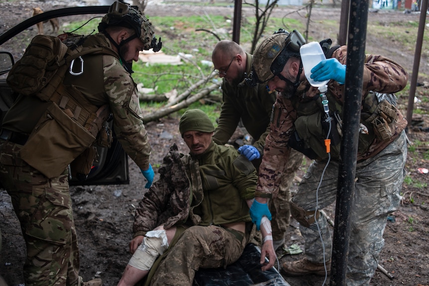 Ukrainian soldiers give first aid to a wounded soldier.