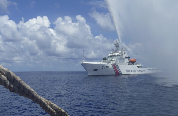 FILE - Chinese Coast Guard members approach Filipino fishermen as they confront each other off Scarborough Shoal in the South China Sea on Sept. 23, 2015. China's coast guard claimed Tuesday, Oct. 10, 2023, to have chased a Philippine navy ship from a disputed shoal in the South China Sea as tensions between the two countries over rich fishing areas escalate. (AP Photo/Renato Etac, File)