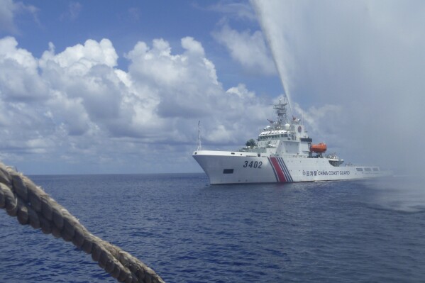 FILE - Chinese Coast Guard members approach Filipino fishermen as they confront each other off Scarborough Shoal in the South China Sea on Sept. 23, 2015. China's coast guard claimed Tuesday, Oct. 10, 2023, to have chased a Philippine navy ship from a disputed shoal in the South China Sea as tensions between the two countries over rich fishing areas escalate. (AP Photo/Renato Etac, File)