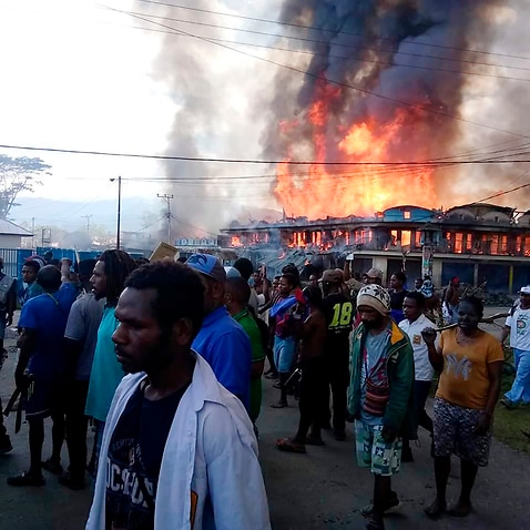 People gather as shops burn in the background during a protest in Wamena on 23 September.