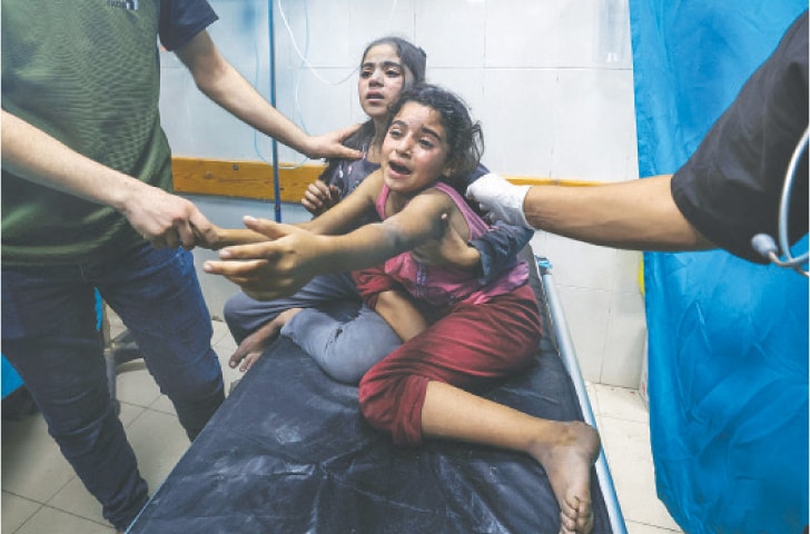  Children injured in an Israeli air strike react as they receive treatment in Nasser Hospital in Khan Yunis, in the southern Gaza Strip, on Tuesday. Authorities fear hundreds more are buried under the rubble.—AFP 