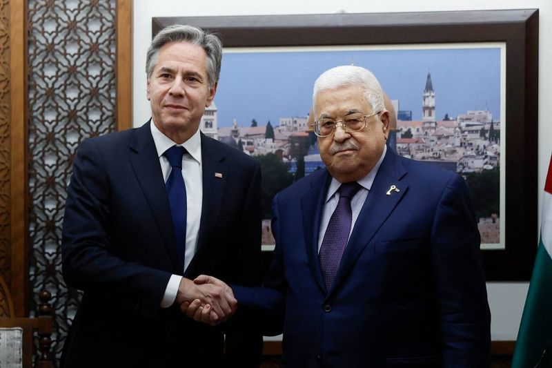 Blinken and Abbas stand side by side and shake hands.