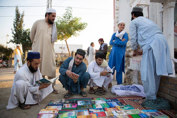 Students looking through Islamic books at a stall on campus during an evening break.