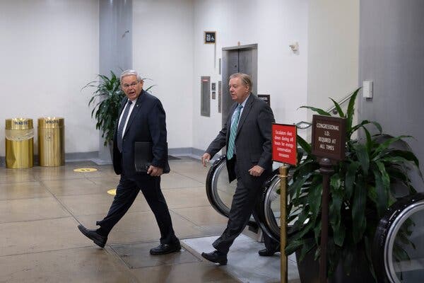 Two men wearing suits walking in a hallway in the Capitol.