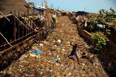 1403533385-a-boy-wades-on-a-layer-of-rubbish-over-a-river-susans-bay-freetown-450x299.jpg