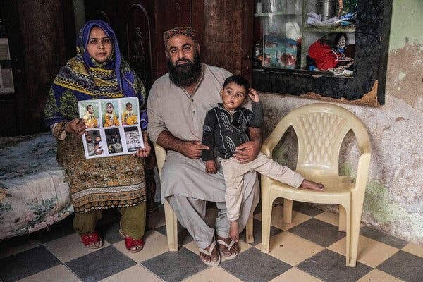 Zahid Meerani with his son and wife. She is holding photographs of another son, Ghulam Nabi Meerani, who died of H.I.V. when he was 2.