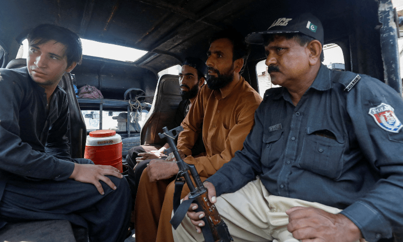  A police officer sits with detained Afghan nationals, who according to them were undocumented, as they shift them to a holding centre, after Pakistan gave the last warning to undocumented migrants to leave, in Karachi, Pakistan on Nov 1. — Reuters 