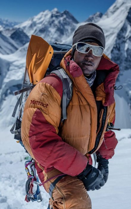 Sajid Sadpara of Pakistan posing for a photo in an orange high-altitude suit