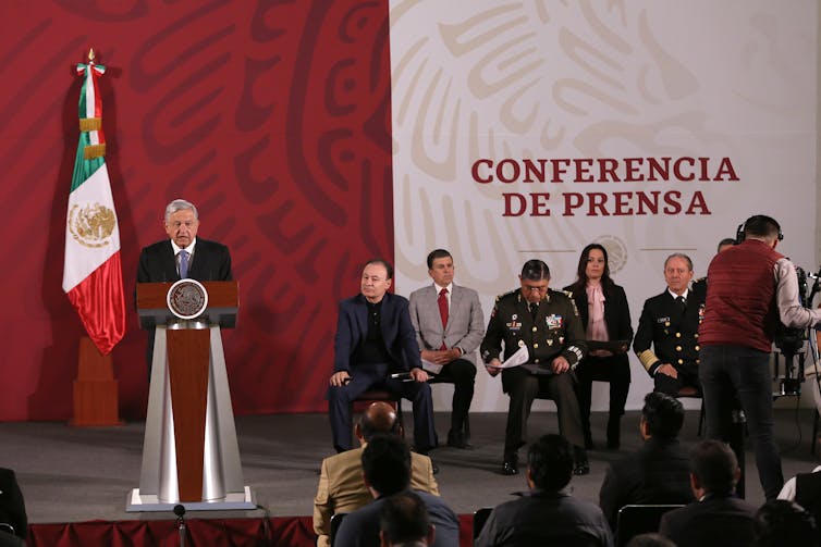 Mexico's president speaks at a lectern on a stage with a small crowd of government officials sitting nearby's president speaks at a lectern on a stage with a small crowd of government officials sitting nearby