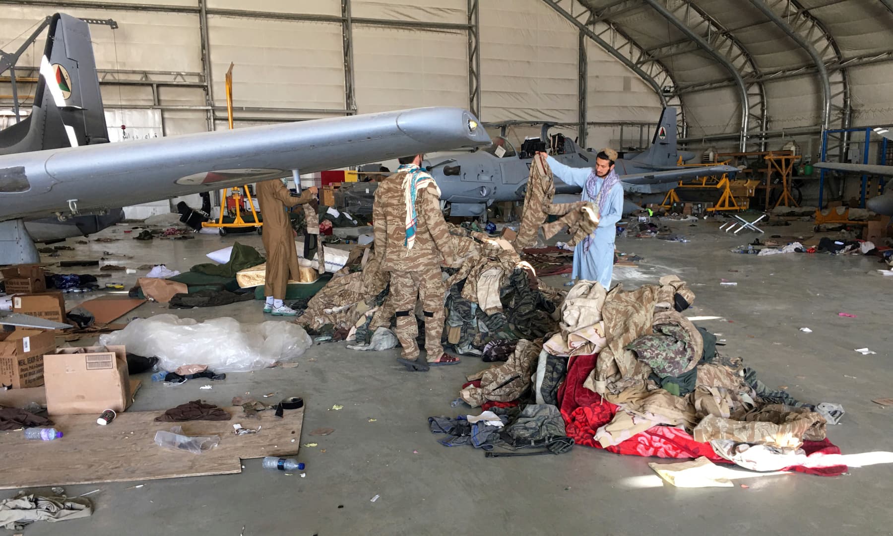 Taliban fighters collect military clothes near damaged Afghan military aircraft after the Taliban's takeover inside the Hamid Karzai International Airport in Kabul, Afghanistan on September 5, 2021. — AP