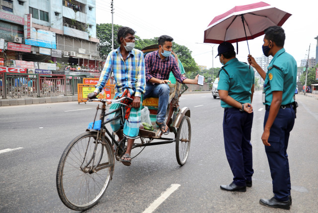 Police officers check commuters at a checkpost during a countrywide lockdown, in Dhaka, Bangladesh, July 1, 2021. (photo credit: REUTERS/MOHAMMAD PONIR HOSSAIN)