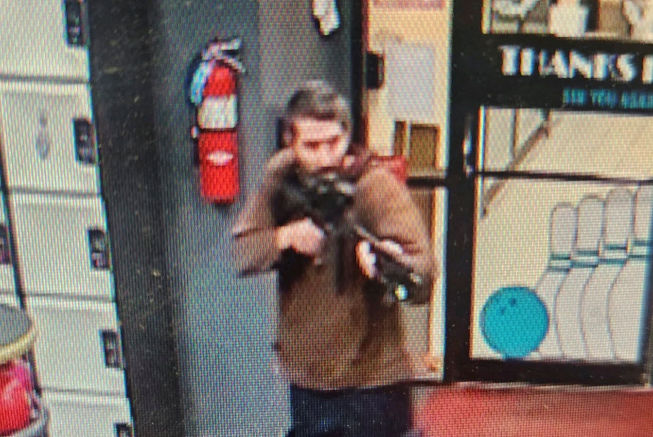 A man identified as a suspect by police points what appears to be a semiautomatic rifle, in Lewiston