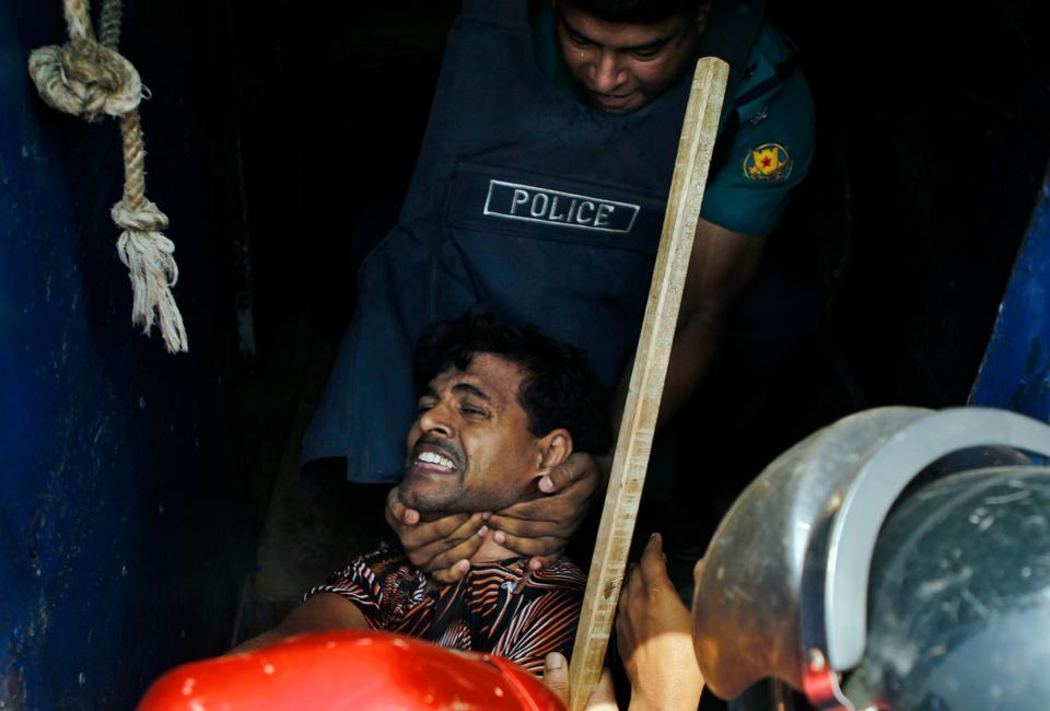 Bangladeshi policemen detain a man following clashes between local Bengali youths and Biharis at the Geneva camp in Dhaka, Bangladesh, Saturday, June 14, 2014.