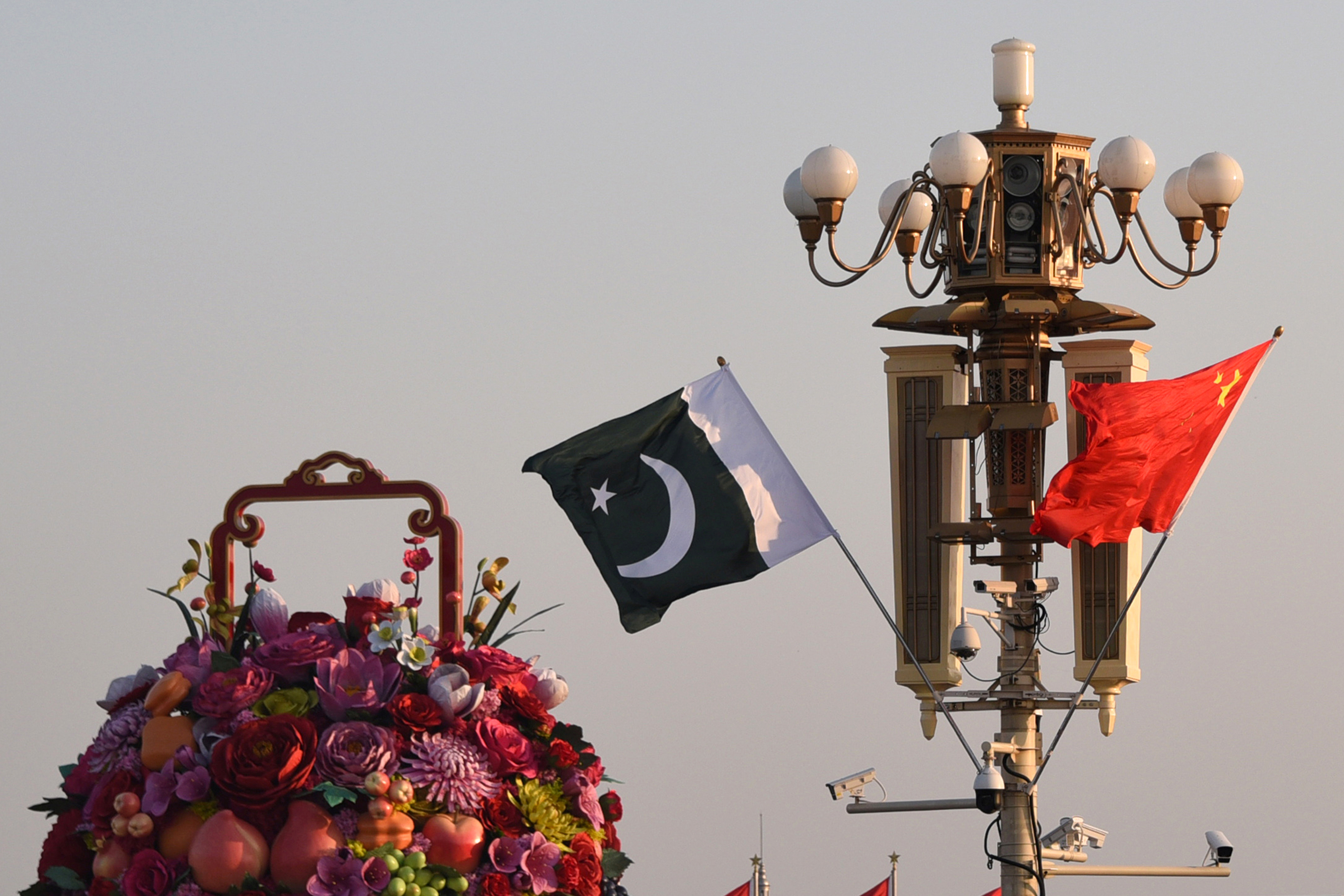 Pakistani and Chinese national flags flutter next to an installation featuring a giant flower basket at the Tiananmen Square in Beijing