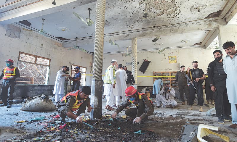 PESHAWAR: Personnel of the Rescue 1122 and bomb disposal squad collect pieces of evidence from the site of the bomb explosion on Tuesday. — Dawn