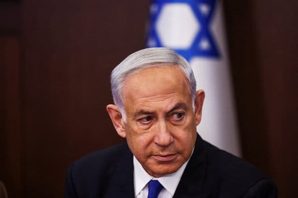 Prime Minister Benjamin Netanyahu of Israel wearing a suit in front of an Israeli flag.