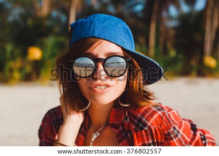 stock-photo-young-beautiful-brunette-girl-in-a-blue-baseball-cap-and-sunglasses-in-hipster-plaid-shirt-poses-376802557.jpg
