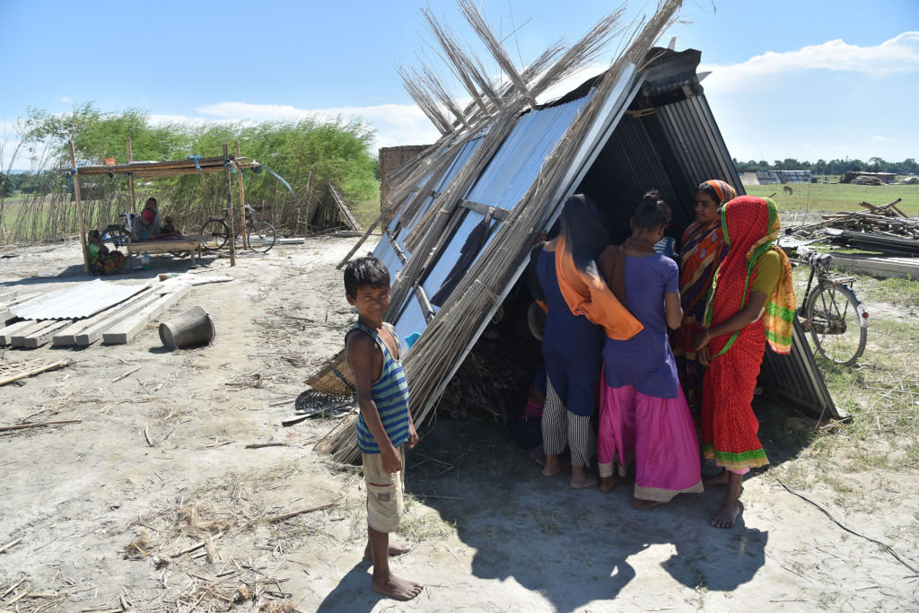 Villagers on Sept. 27 take shelter with their belongings after their house was demolished during an eviction drive, at Gorukhuti in the Darrang district of Assam, India (Anuwar Ali Hazarika/Barcroft Media via Getty Images)
