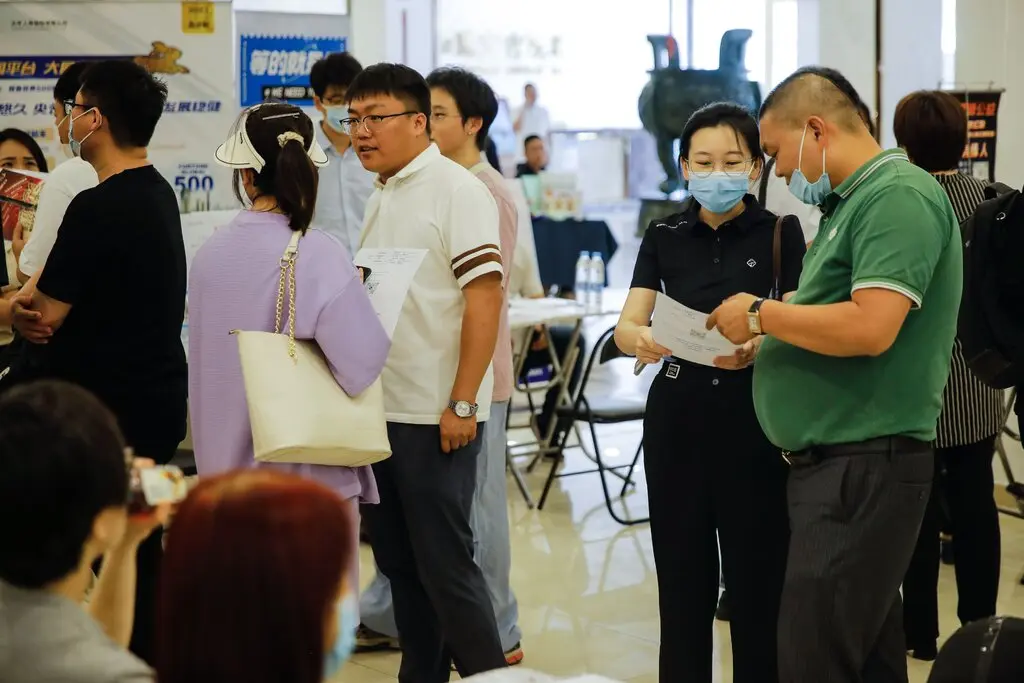 About half a dozen of people, several chatting with one another, at a job fair in Beijing.
