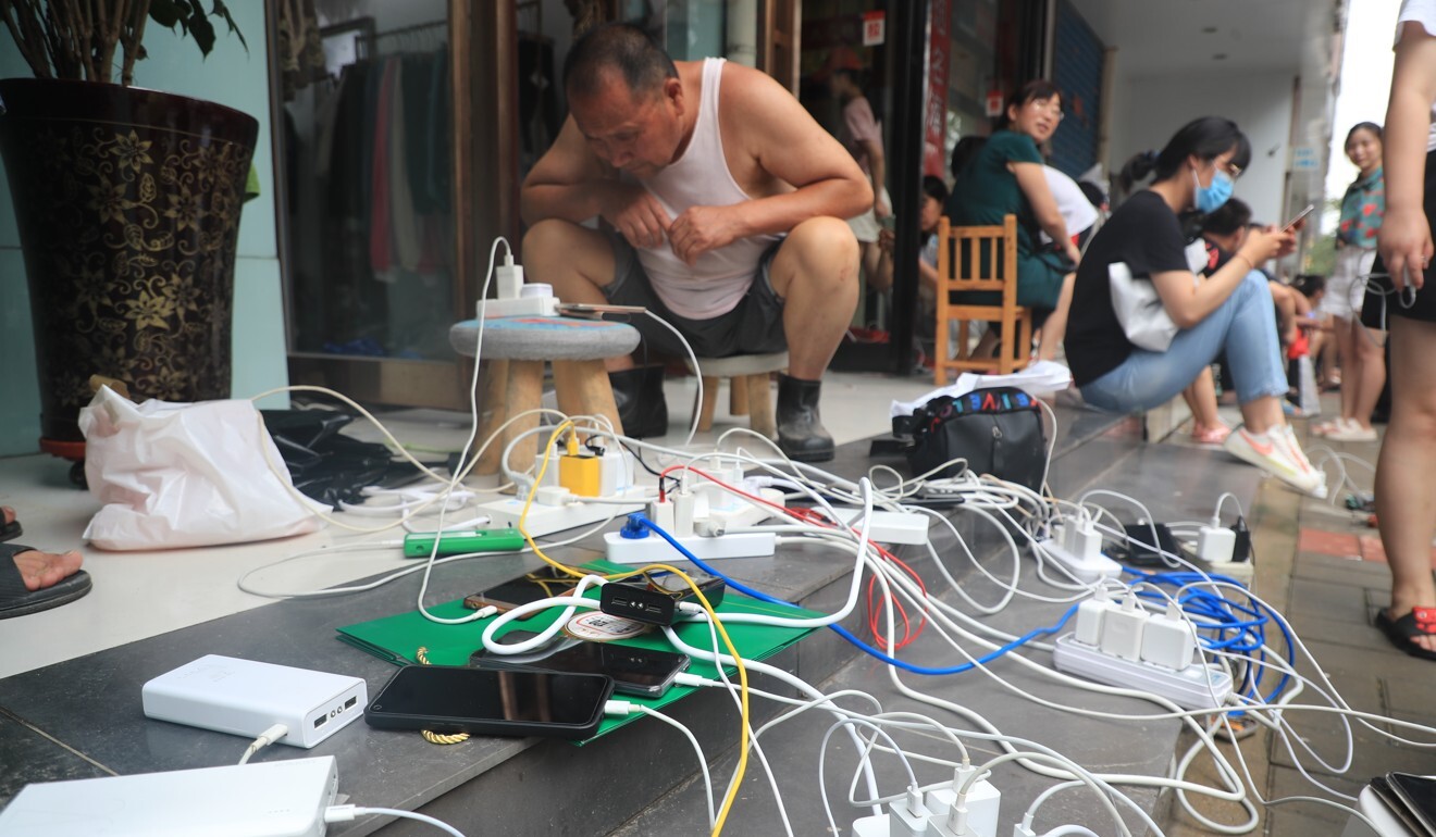 People charge mobile phones outside a shop in Zhengzhou that had electricity. Photo: Getty Images