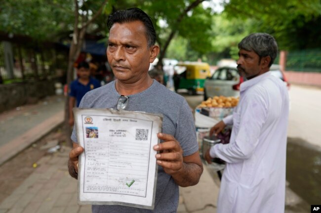Roadside vendor Shankar Lal shows his government permit to run a stall in New Delhi, India, Thursday, Aug. 24, 2023. Shankar Lal said he hasn't opened his stall, where he sells chickpea curry with fried flatbreads, for three months after authorities told him to move away. The government doesn't know whether we are dying of hunger or not, Lal said. (AP Photo/Manish Swarup)