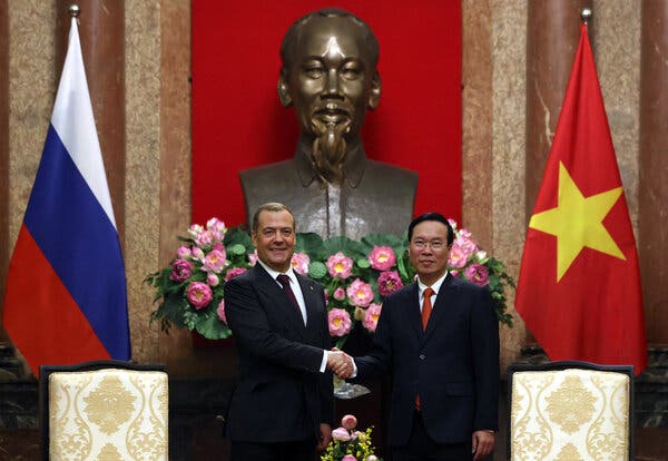 Dmitri A. Medvedev and Vo Van Thuong stand side by side, shaking hands and looking forward. They are flanked by flags of Russia and Vietnam.