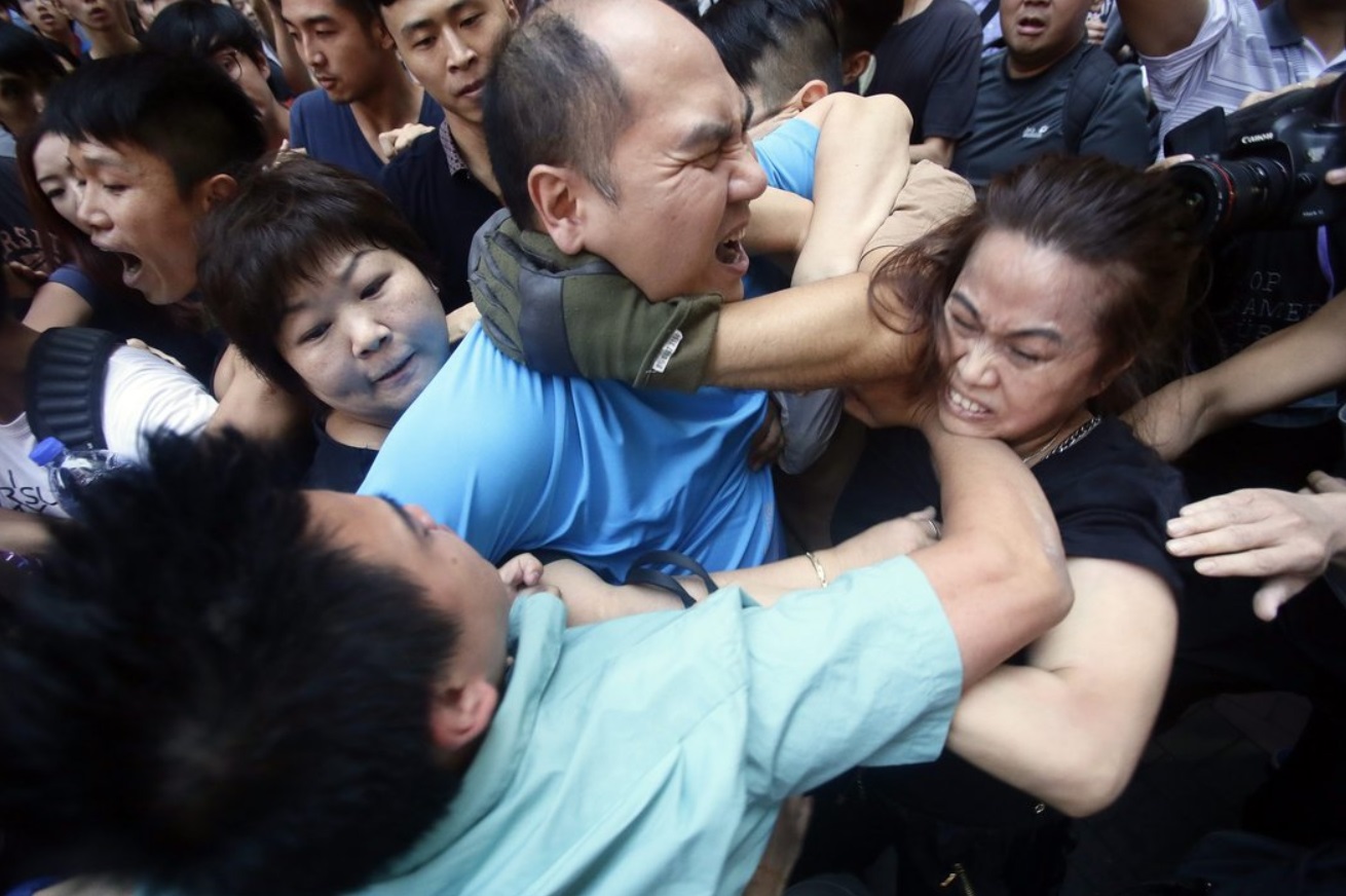 An opponent of the pro-democracy campaign, center, was grabbed by protesters.jpg