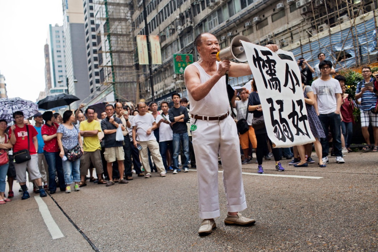 Confronting pro-democracy demonstrators on Saturday, a man held up a banner and yelled abuse.jpg