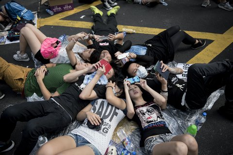 Demonstrators checked their cellphones on Nathan Road, a major route through Kowloon, on Monday.jpg