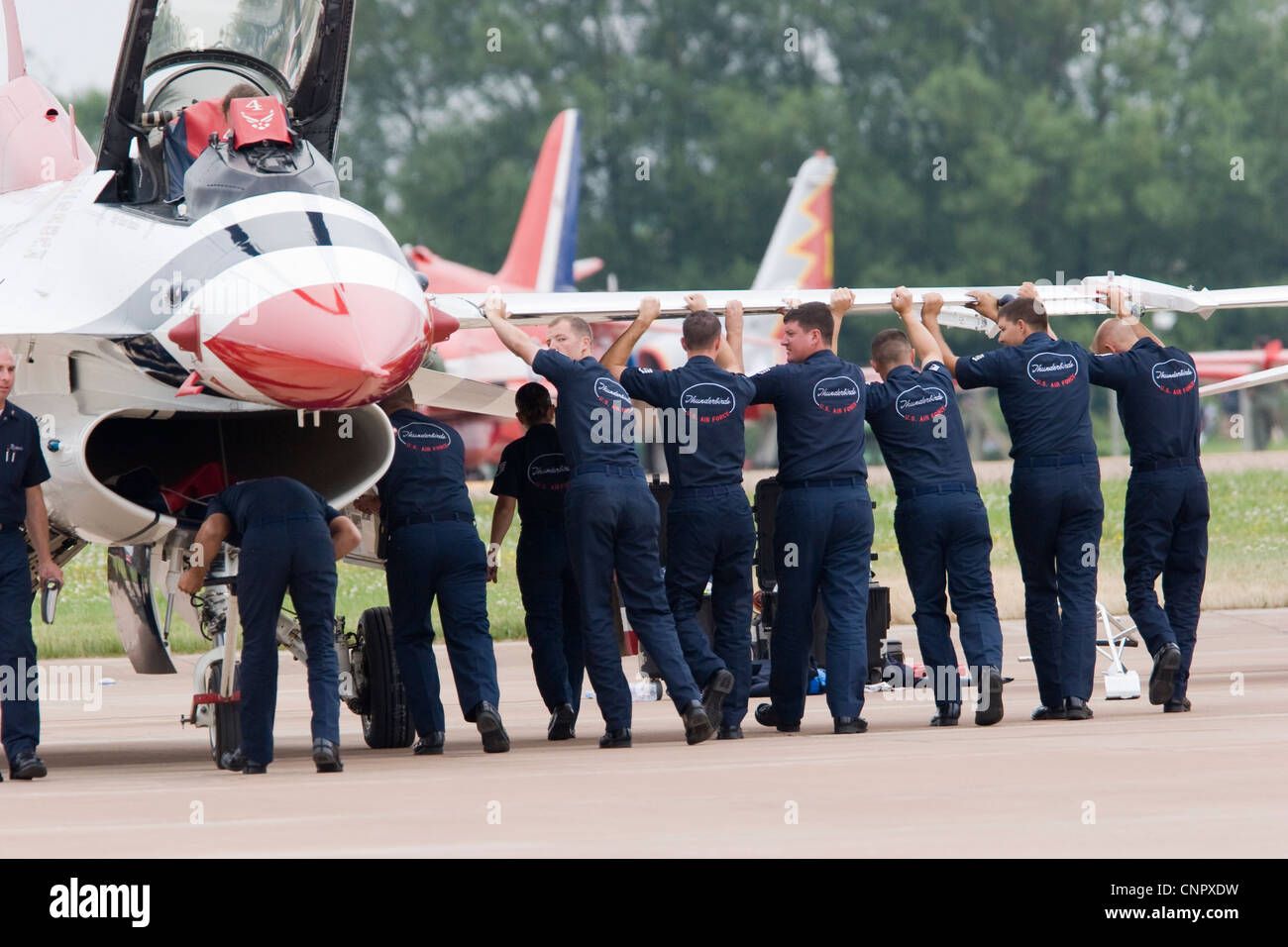 ground-crew-pushing-an-f16-fighter-jet-one-of-the-aircraft-in-the-CNPXDW.jpg