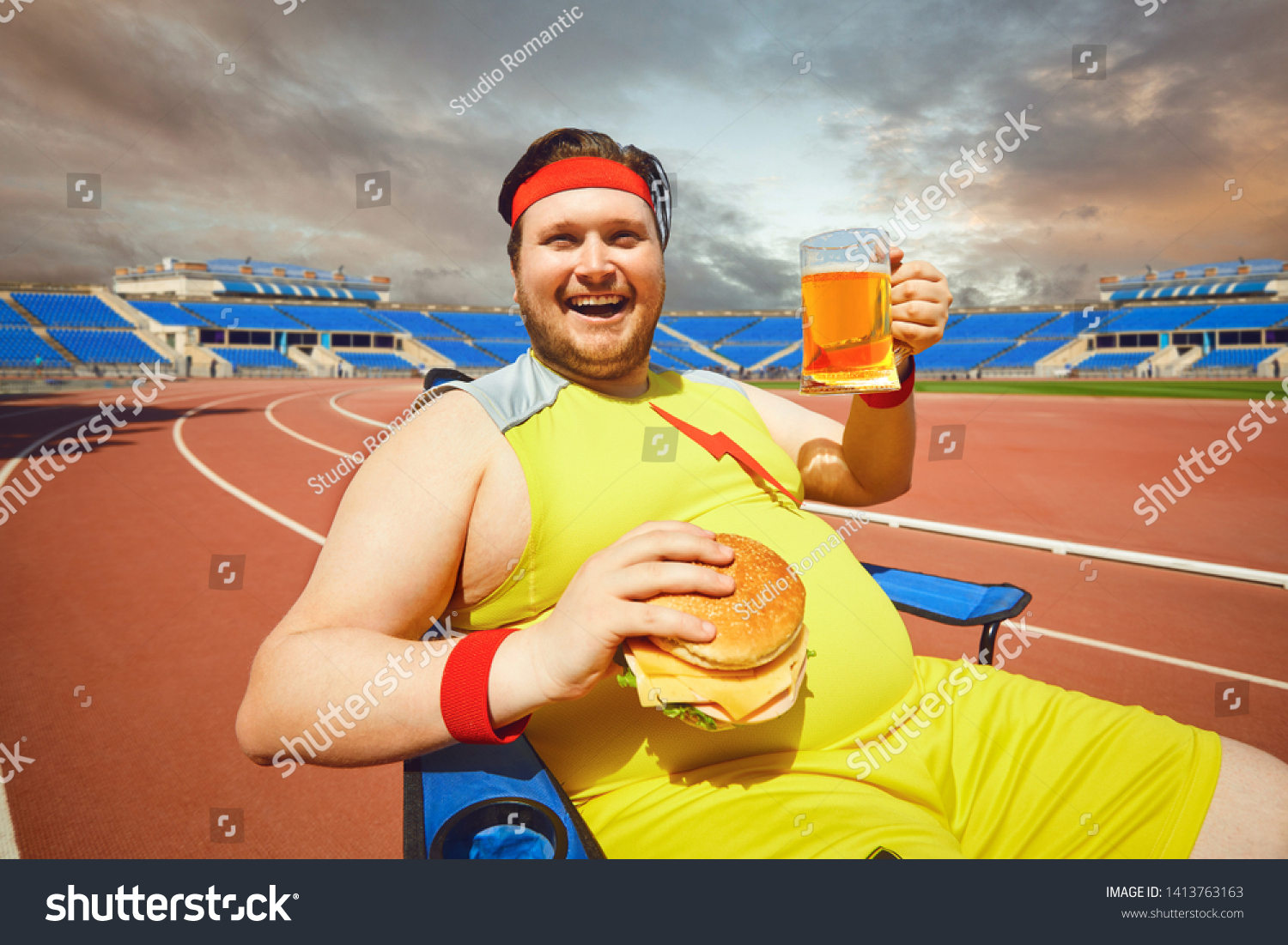stock-photo-fat-man-eating-a-burger-and-beer-in-training-at-the-stadium-1413763163.jpg
