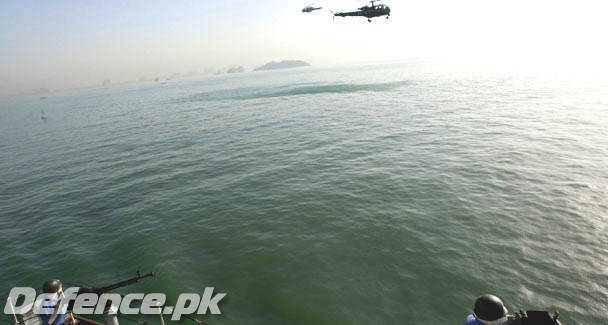 A Pakistan Navy soldier (L) operates an anti-aircraft weapon as helicopters