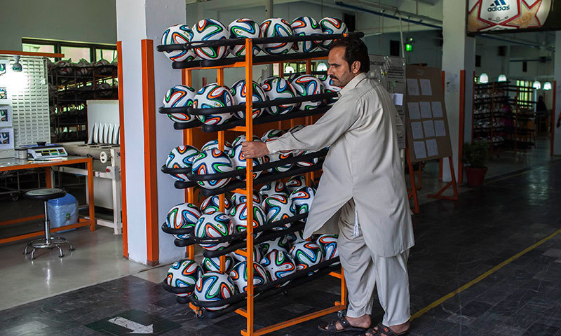 An employee takes finished balls out of the production area inside a football factory in Sialkot. — Reuters/File