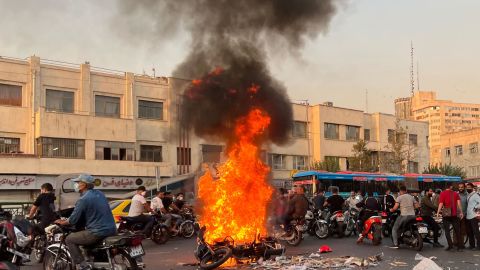 People gather next to a burning motorcycle in the Iranian capital Tehran on October 8, 2022.