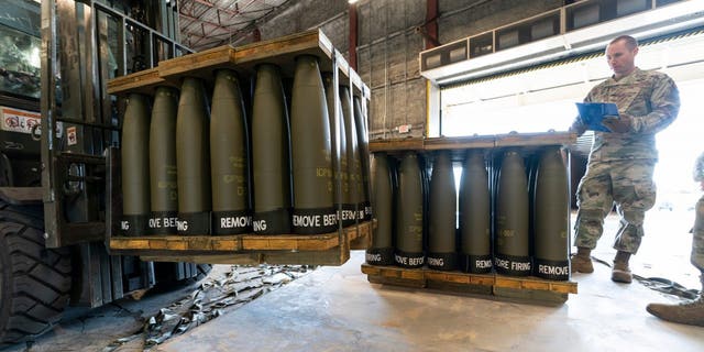 U.S. Air Force Staff Sgt. Cody Brown, right, with the 436th Aerial Port Squadron, checks pallets of 155 mm shells ultimately bound for Ukraine, April 29, 2022, at Dover Air Force Base, Delaware.