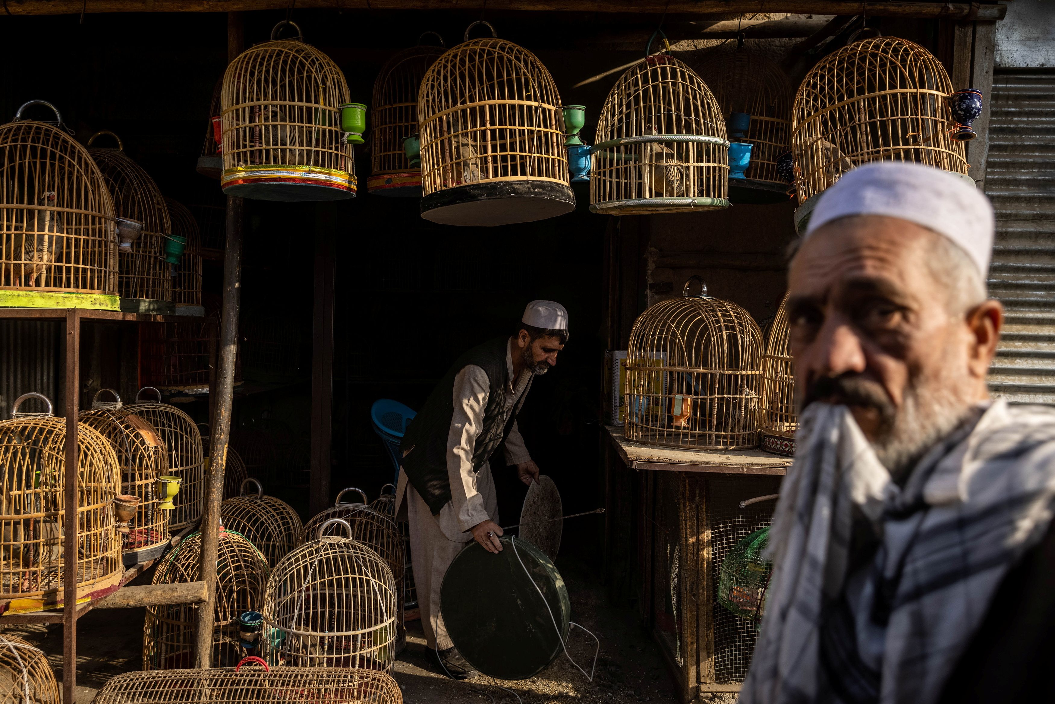 A man selling partridges cleans their cages at a market in Kabul