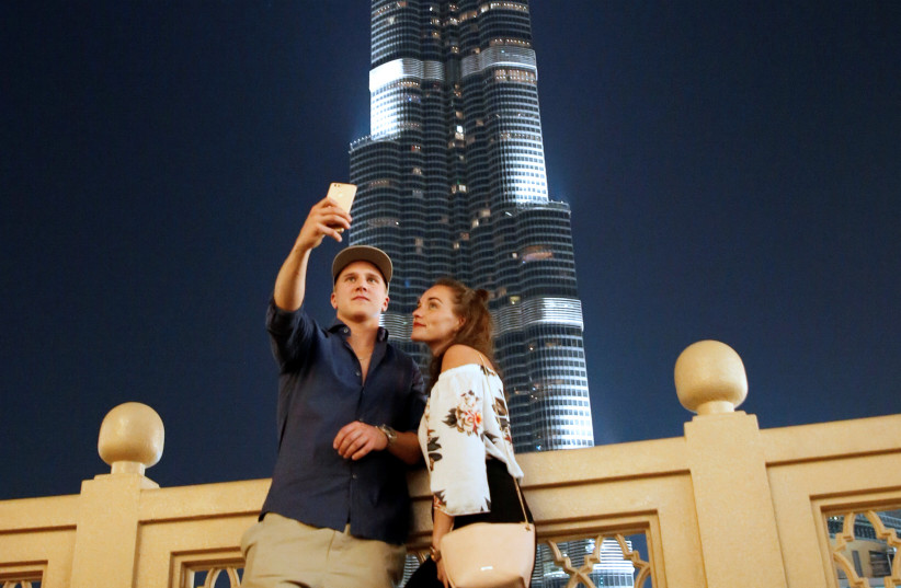  A TOURIST COUPLE takes a photo in front of Burj Khalifa, the tallest tower in the world, in Dubai, UAE. (credit: AMR ABDALLAH DALSH / REUTERS)