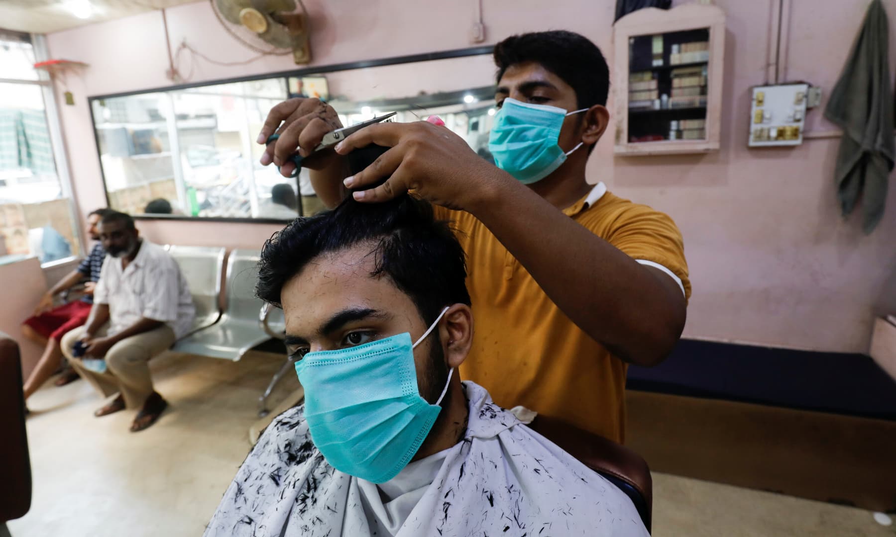 A man wears a protective mask as he gets a haircut at a barbershop in Karachi, August 10. — Reuters