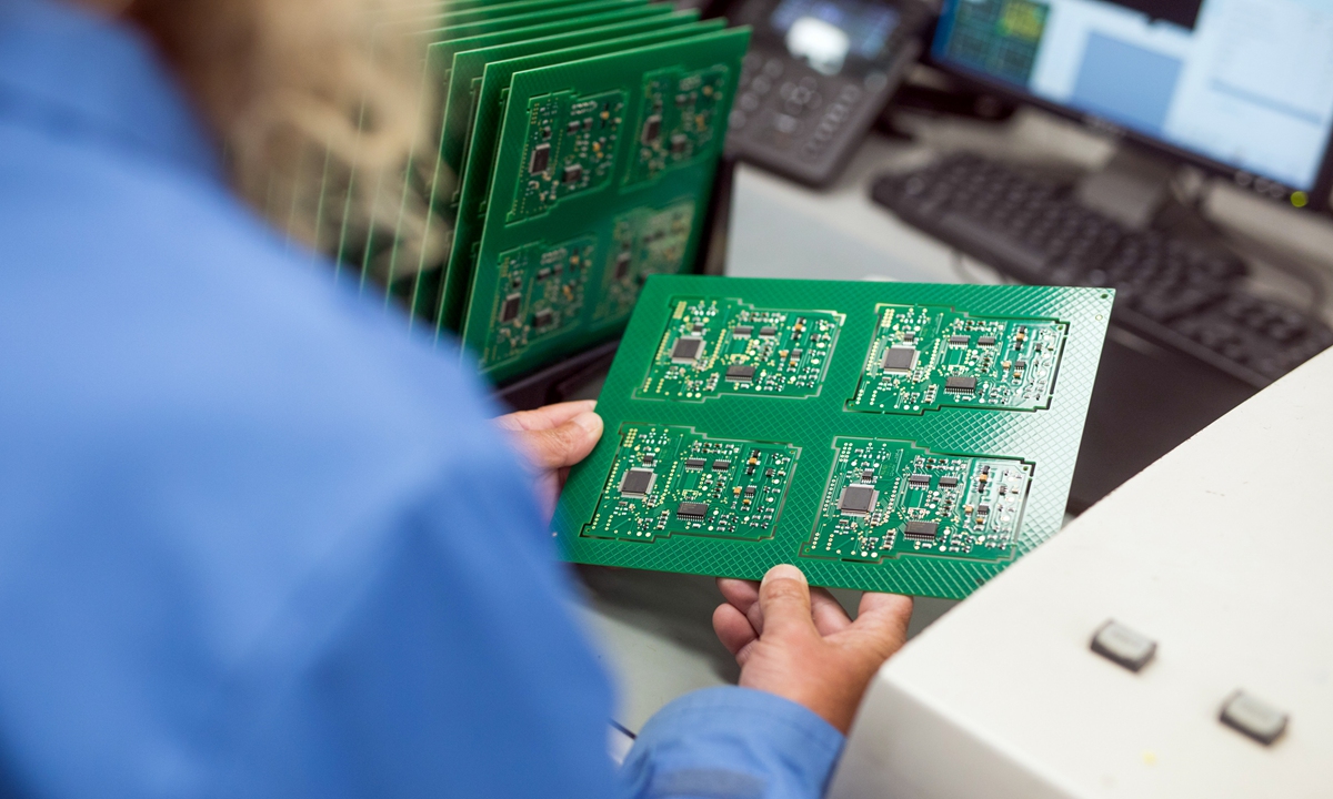 An employee checks a printed circuit board containing integrated circuit microchips at CSI Electronic Manufacturing Services Ltd. in Witham, the UK, on April 28, 2021. Photo: VCG