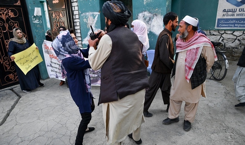 A woman protester scuffles with a member of the Taliban during a demonstration outside a school in Kabul on Thursday. — AFP