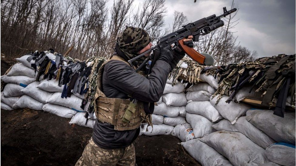A Ukrainian serviceman shoots at a Russian drone with an assault rifle from a trench at the front line east of Kharkiv