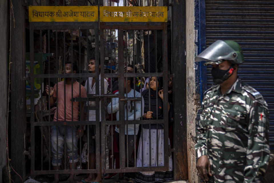 An Indian paramilitary solider stands guard as residents watch from behind a bolted iron gate during the demolition of Muslim-owned shops in New Delhi's northwest Jahangirpuri neighborhood on April 20, 2022.<span class=copyright>Altaf Qadri/AP</span>