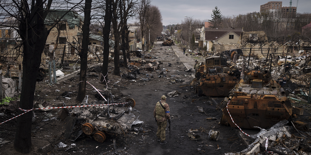 A Ukrainian serviceman walks amid destroyed Russian tanks in Bucha on the outskirts of Kyiv, Ukraine.