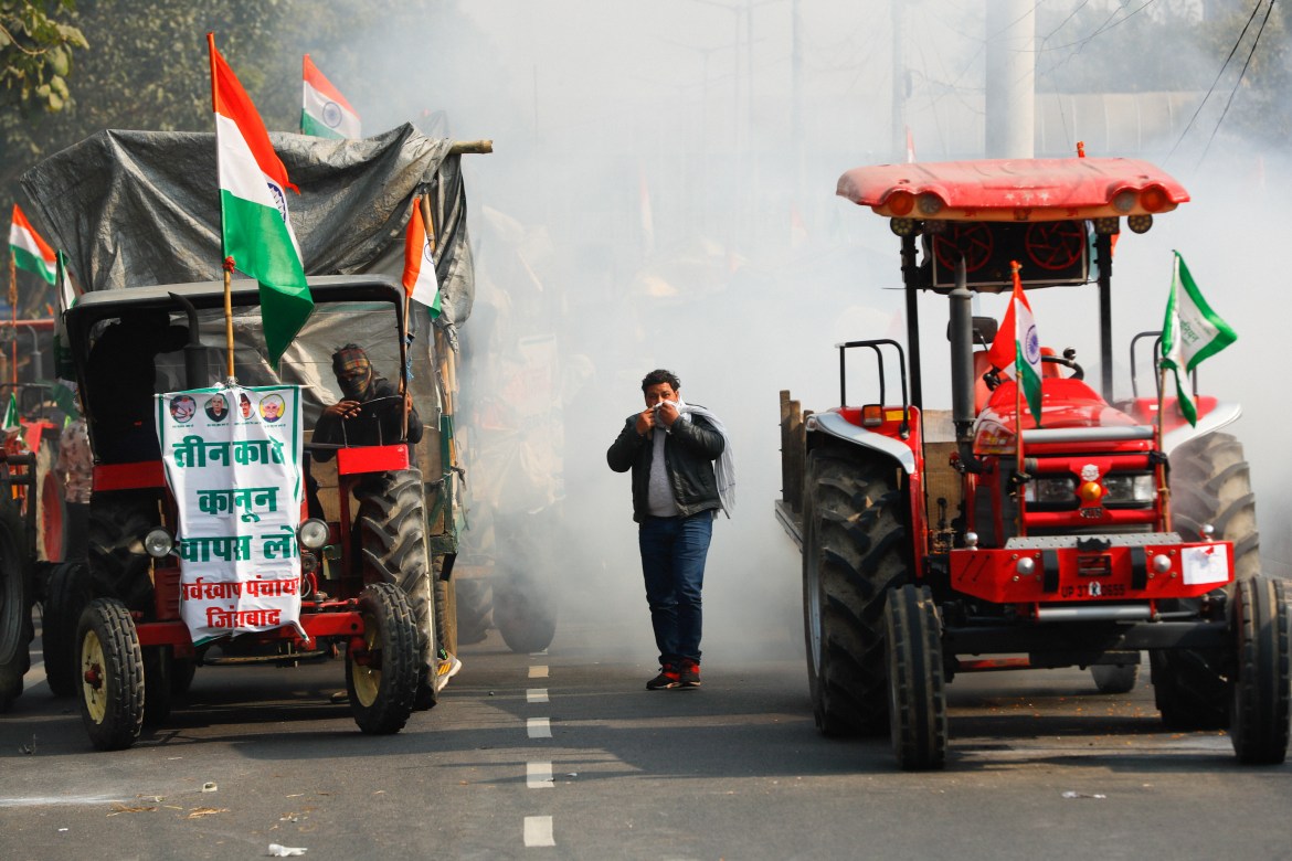 A farmer covers his face to protect himself from tear gas during the protest in New Delhi. [Adnan Abidi/Reuters]